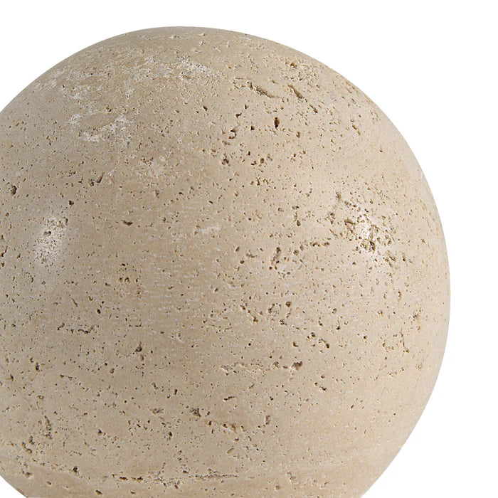 Extreme close-up of the Geo travertine decorative sphere, highlighting the natural beige color and porous stone texture.
