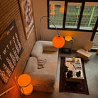 Goldenhour Adjustable Arc Floor Lamp casting warm amber light beside a cozy sofa in modern loft living room