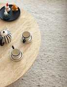 Harmony Travertine Coffee Table top view with striped teapot and matching cups on neutral textured rug