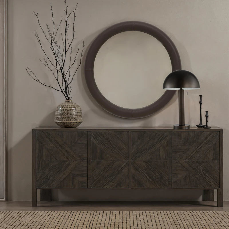 Harrison bronze table lamp styled on a dark wood sideboard in a modern entryway with a round mirror and ceramic decor.