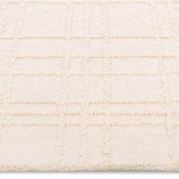 Macro close-up of the raised tufted geometric grid pattern and soft cream pile on the Hayes textured area rug.