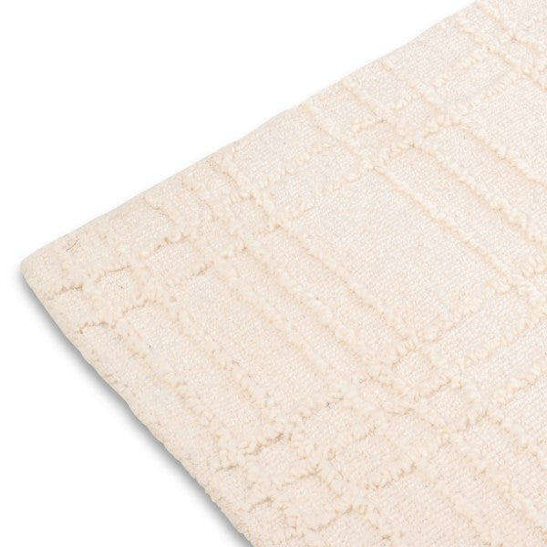 Corner view of the cream Hayes textured grid rug highlighting its tidy bound edge and high-low tufted pattern.