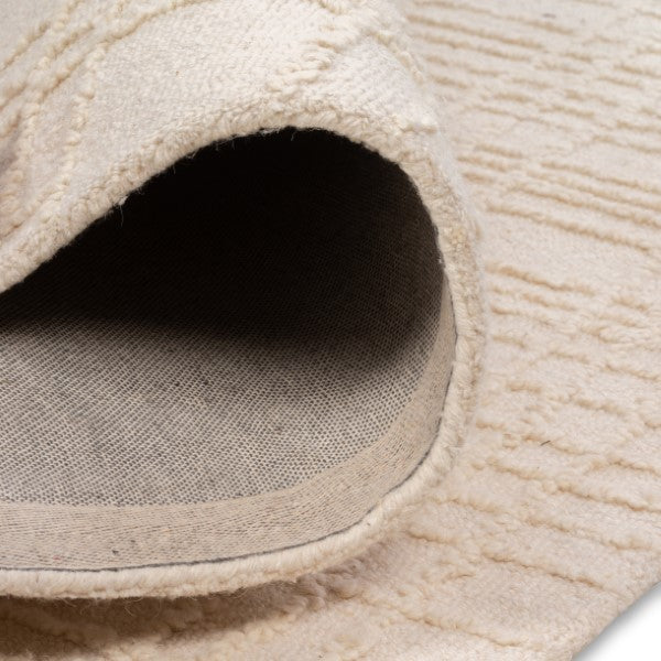 Rolled edge of the Hayes cream grid rug showcasing its soft textured top pile and durable woven backing.