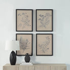 Herbarium Noir botanical wall art set hanging on a white wall above a wooden console table with a black lamp for modern home decor
