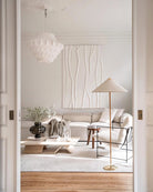 Horizon Shade Floor Lamp with brass base and linen cone shade in a minimalist neutral living room with cream sofa and wood accents