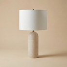 Table lamp with a beige ceramic base and white shade on a beige background