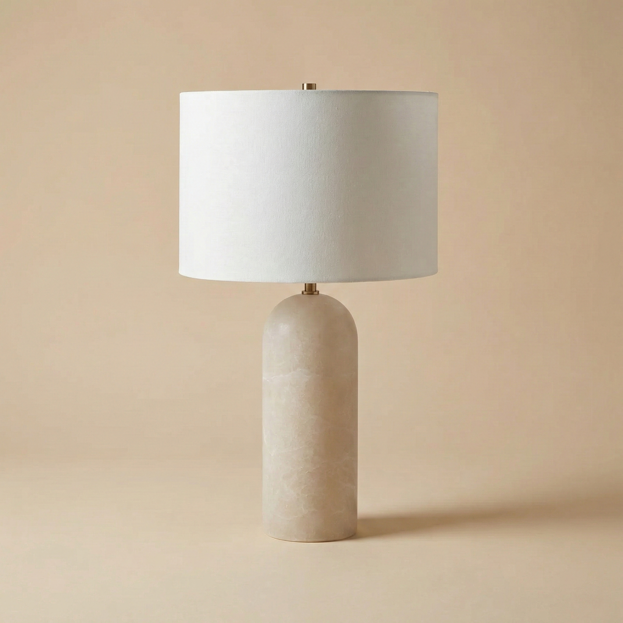 Table lamp with a beige ceramic base and white shade on a beige background