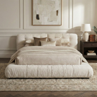 Front view of the cream Italian-style cloud bed styled with neutral bedding and a vintage rug in a soft, modern bedroom.