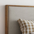 Lena Storage Bed headboard close-up showing upholstered fabric and wood frame against a light wall background