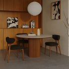 Lucia Dining Table styled in a cozy dining nook with warm wood cabinets, paper lantern light, and dark fabric chairs