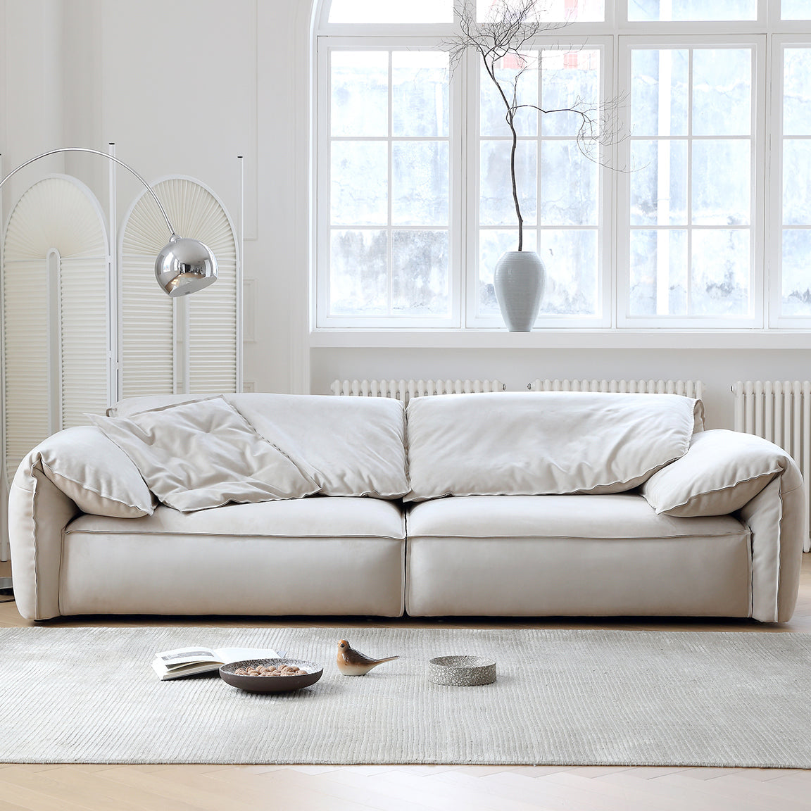 Luxury Elephant Ear Sofa in cream ultra suede placed in a bright living room with large windows and neutral decor