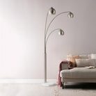 Lyra Arc Floor Lamp with triple curved arms beside beige sofa in modern living room