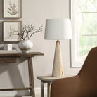 Marlo Travertine Table Lamp on round side table beside brown chair and wooden console in cozy living room