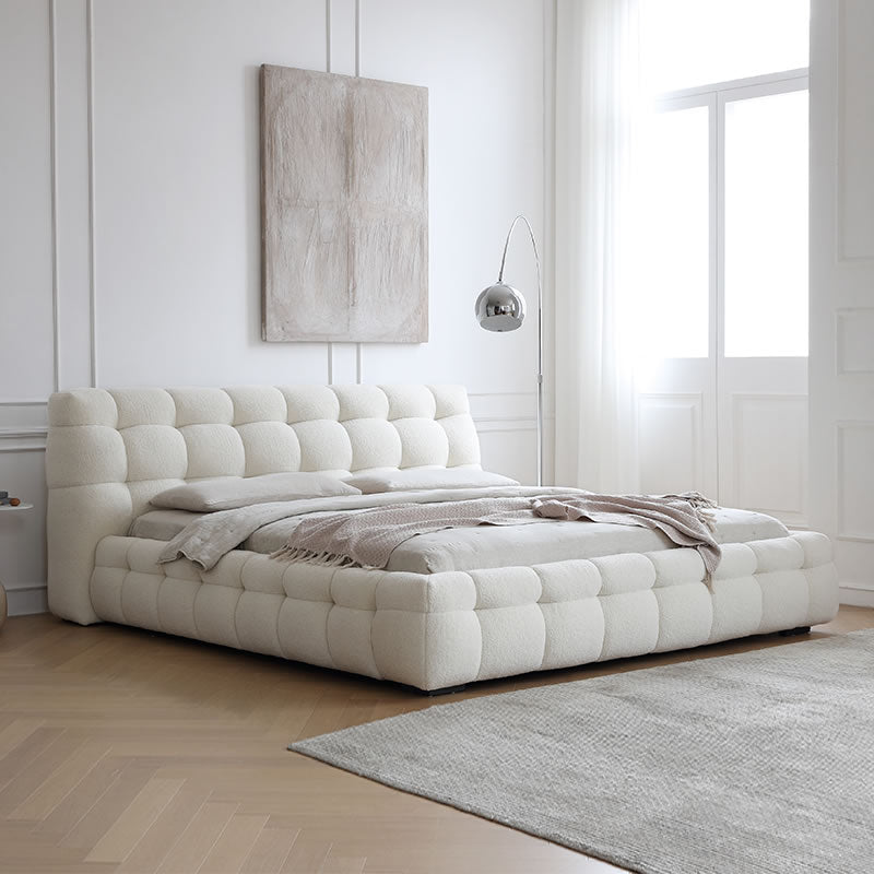 Marshmallow Puff Bed in white boucle upholstery styled in a bright modern bedroom with floor lamp and soft neutral decor