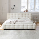 Marshmallow Puff Bed in ivory boucle fabric with tufted frame and pillows styled in a sunlit modern bedroom with floor lamp