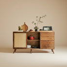Mid-Century Rattan Craft Sideboard with sliding cane door and open shelving styled with cookware and decor.