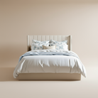 Full front view of the Mila upholstered storage bed featuring a cream vertical channeled wingback headboard and crisp white bedding.