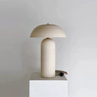 Mira Ceramic Table Lamp with rounded base and dome shade displayed on white pedestal in minimal studio setting