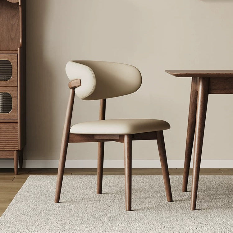 Modern Leather Ash Wood Dining Side Chair in a warm dining room setting, featuring curved upholstery and solid ash wood frame