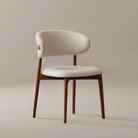Modern Leather Ash Wood Dining Side Chair with curved upholstered backrest and warm ash wood legs on a neutral studio backdrop.