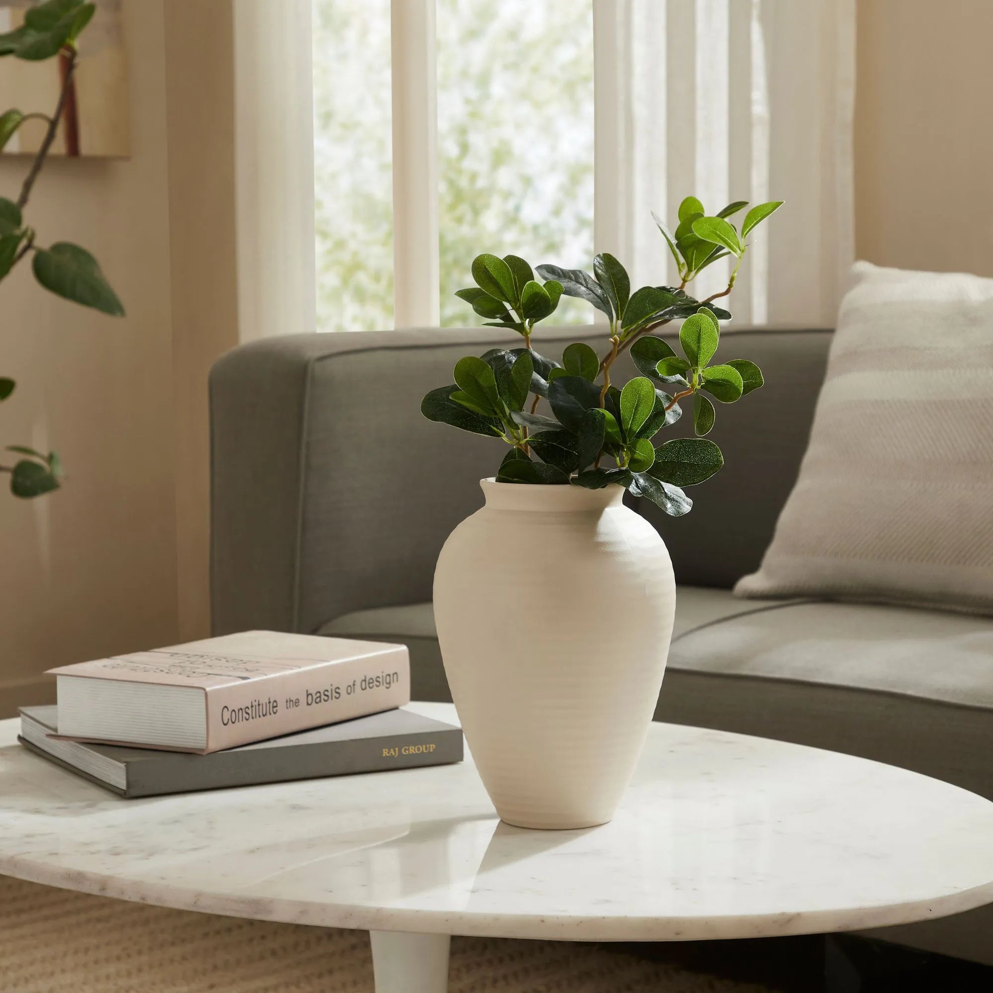 Nara Ceramic Vase with green foliage styled on a marble coffee table in a cozy modern living room