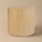 Oaklyn sculpted wood side table featuring a cylindrical drum shape with vertical fluted texture and natural light wood finish.