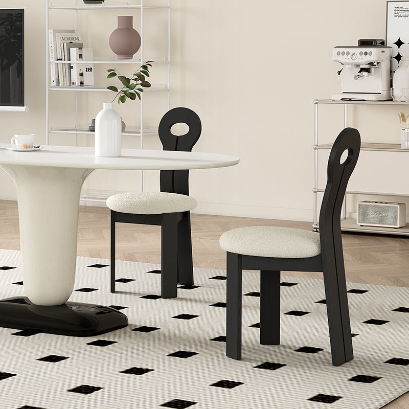 Obsidian Loop Dining Chair styled in a modern dining space, featuring a sculpted black looped backrest and soft bouclé seat