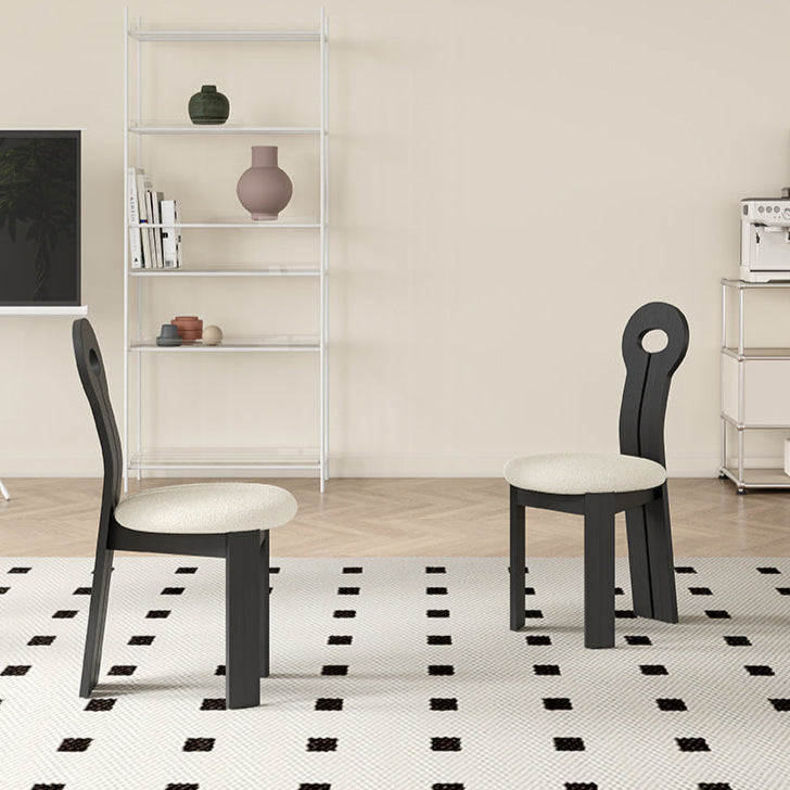 Two Obsidian Loop Dining Chairs with black sculpted backrests and cream bouclé seats styled in a minimal dining room