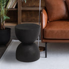 Onda black wood side table styled next to a leather armchair, highlighting its organic totem design and modern aesthetic.