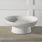 Orla Ceramic Bowl in matte white finish displayed on a wooden table against a paneled white wall