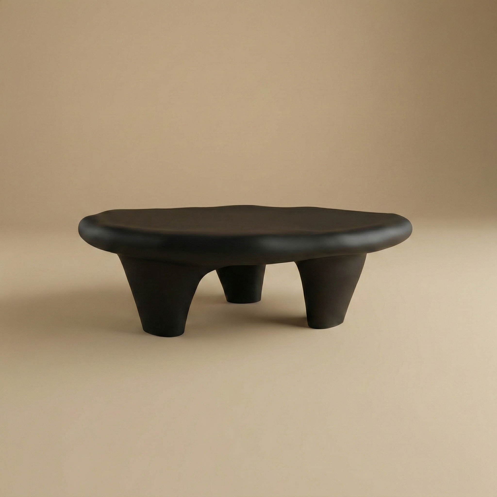 Front view of the matte black pebble coffee table highlighting its sculptural low-profile design.
