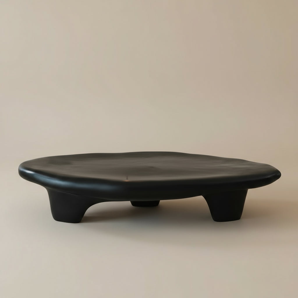 Pebble Coffee Table in matte black finish with organic curved form and low sculptural legs on a neutral background