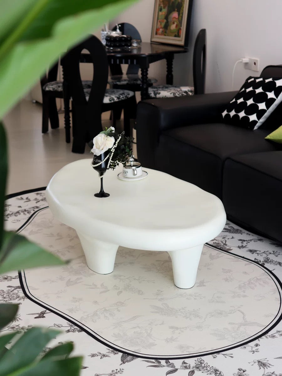 Pebble Coffee Table in matte white finish styled beside black leather sofa with patterned rug and elegant modern decor
