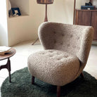 Petra Accent Chair in brown boucle fabric with wooden legs styled in a cozy living room corner on a green rug