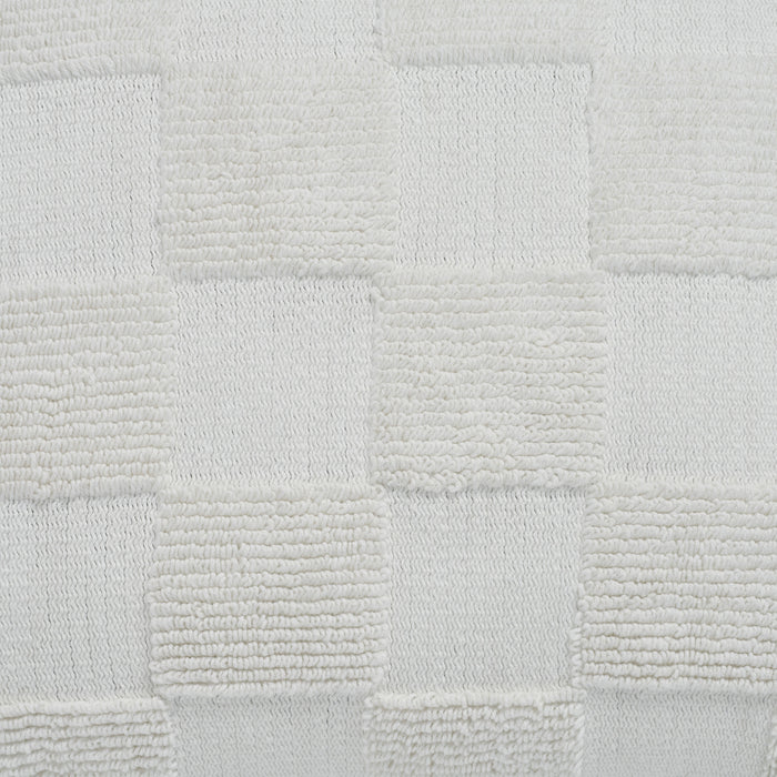 Macro close-up of the raised tufted knitted checkerboard texture on the cream Piper throw pillow.
