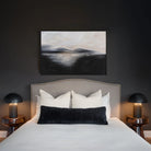 Two cream Sadie knit throw pillows styled behind a black textured lumbar cushion on a bed in a moody, dark-painted bedroom.