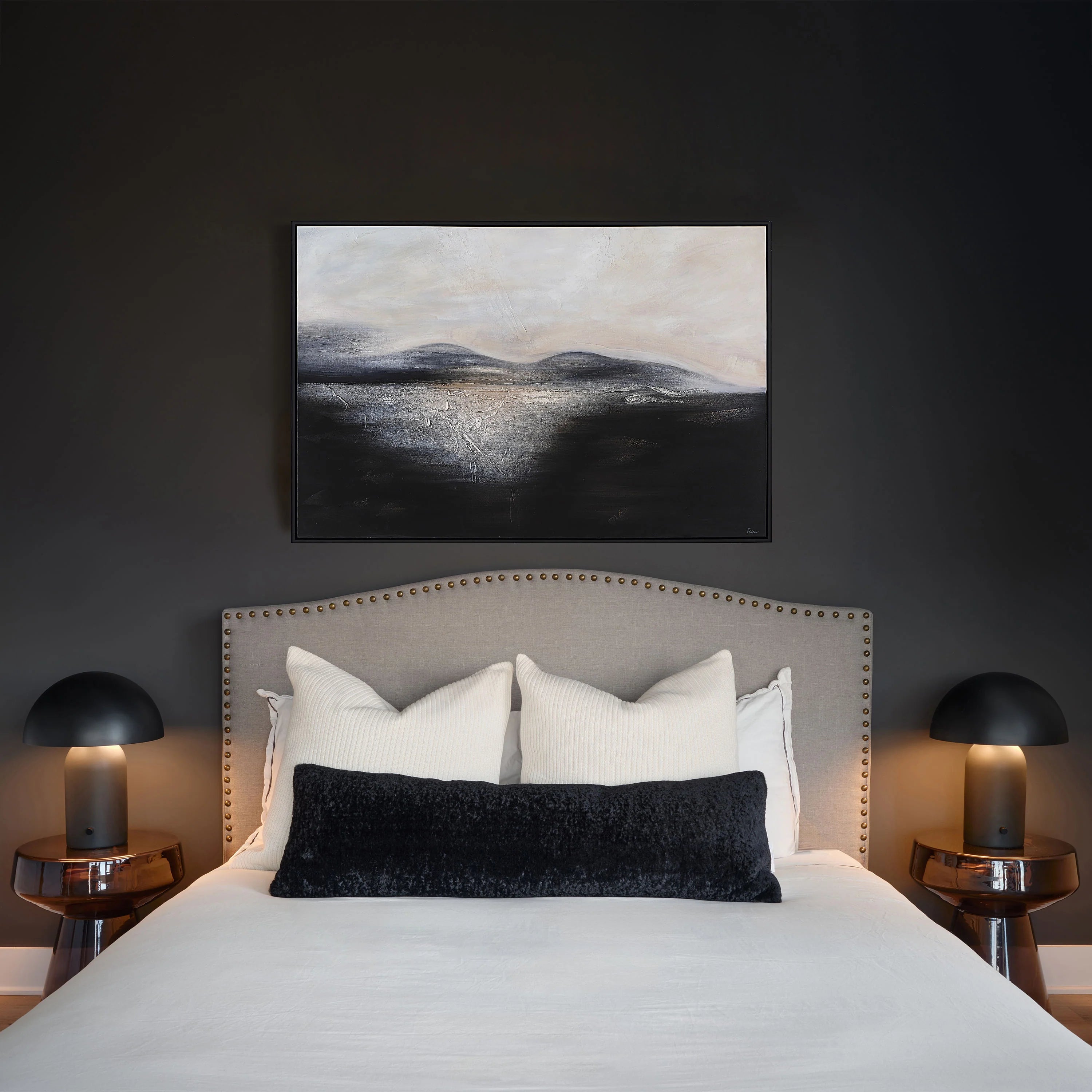 Two cream Sadie knit throw pillows styled behind a black textured lumbar cushion on a bed in a moody, dark-painted bedroom.