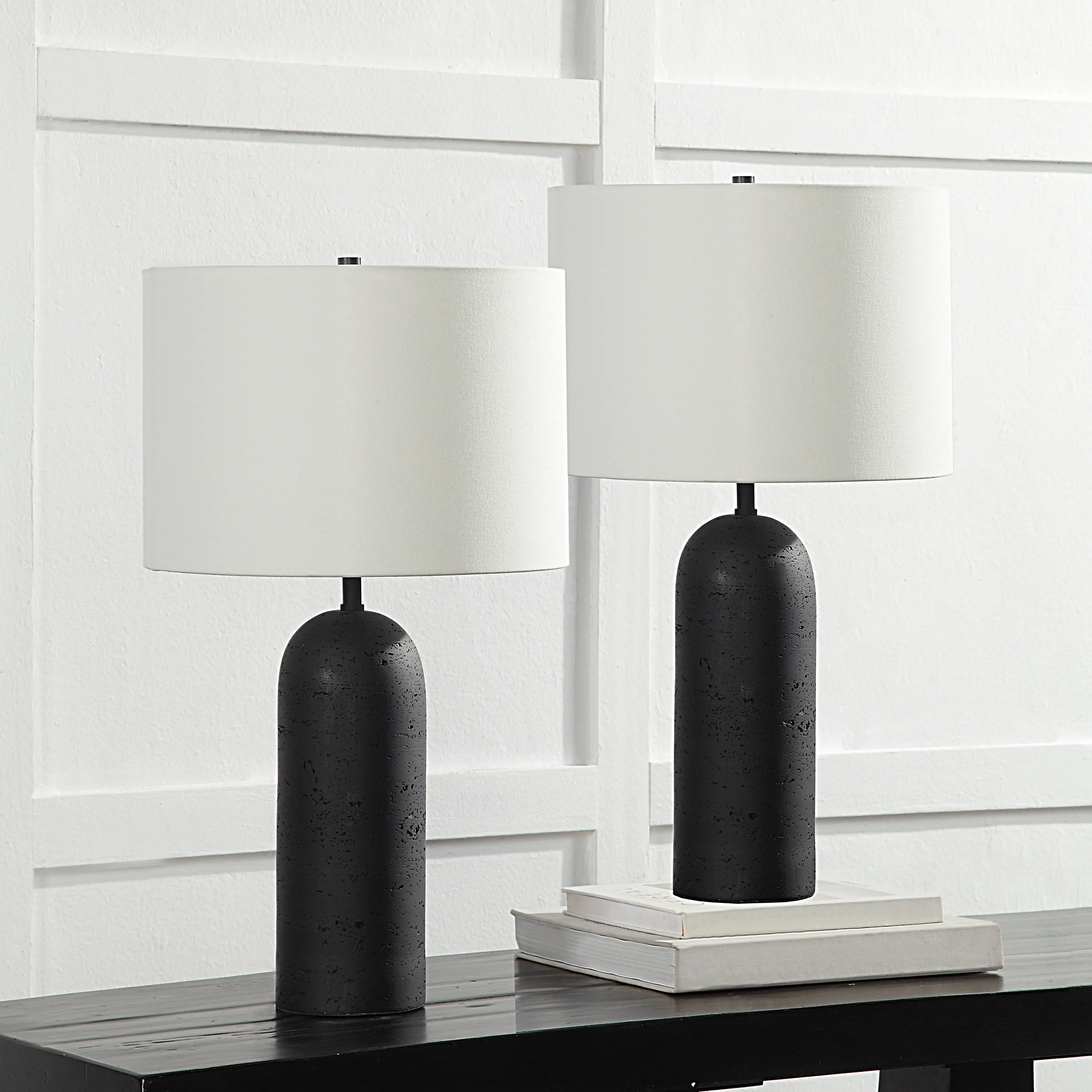 Pair of black Sienna Sculpted Table Lamps with white shades styled on dark console table against white panel wall