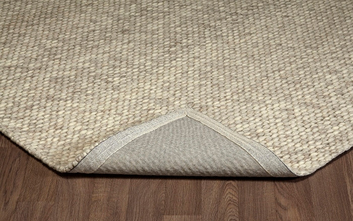 Folded corner of the ivory Silas hand-woven wool rug showing its thick loops and durable woven backing.