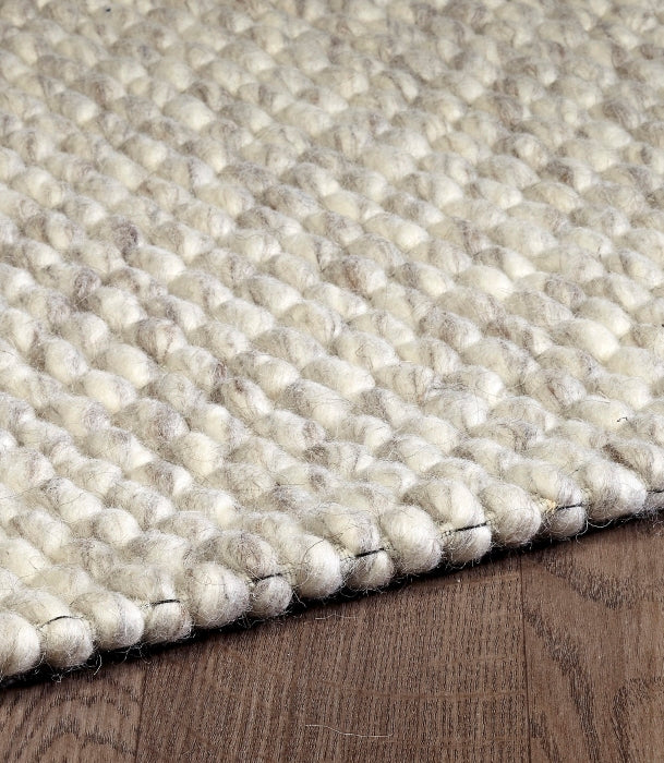 Detailed close-up of the chunky looped pile on the cream ivory Silas hand-woven wool rug.