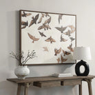 Silent Flight bird painting hanging above a rustic wooden console table with a modern black circular lamp.