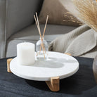Siona Marble Tray styled with a white candle and glass diffuser on a dark coffee table beside a cozy sofa