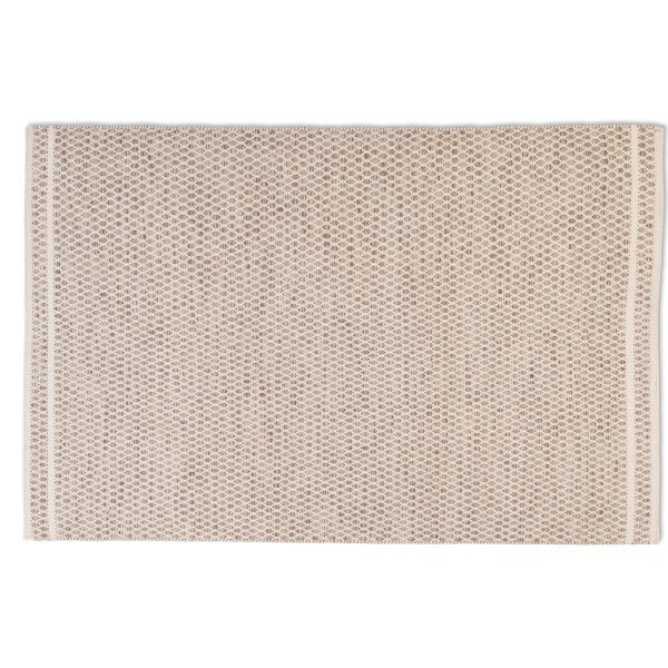 Full top-down view of the Theo hand-woven wool rug in a warm husk oatmeal color, showcasing its geometric woven pattern and banded ends.