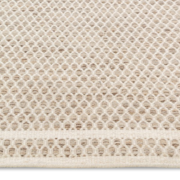 Macro view of the husk Theo rug's surface highlighting the intricate chunky basket weave texture woven from tonal oatmeal wool yarns.