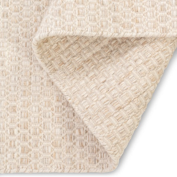 Folded corner of the ivory Theo hand-woven rug showing the identical front and back basketweave pattern typical of flatweave construction.