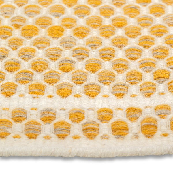 Detailed close-up of the chunky geometric honeycomb weave on the yellow and cream Theo hand-woven wool rug.