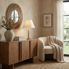 The illuminated Tivoli travertine table lamp styled on a wooden sideboard in a cozy living room with neutral decor.