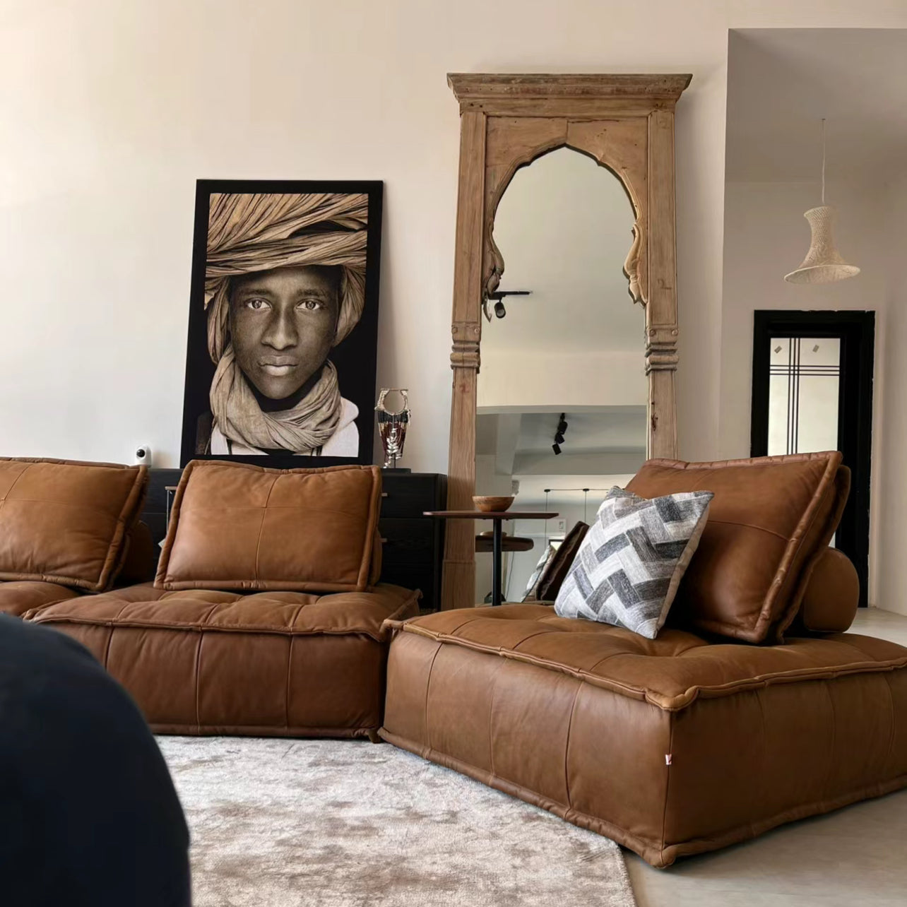 Tofu Modular Sofa in warm brown leather fabric styled in a modern living room with wooden mirror and artistic wall decor