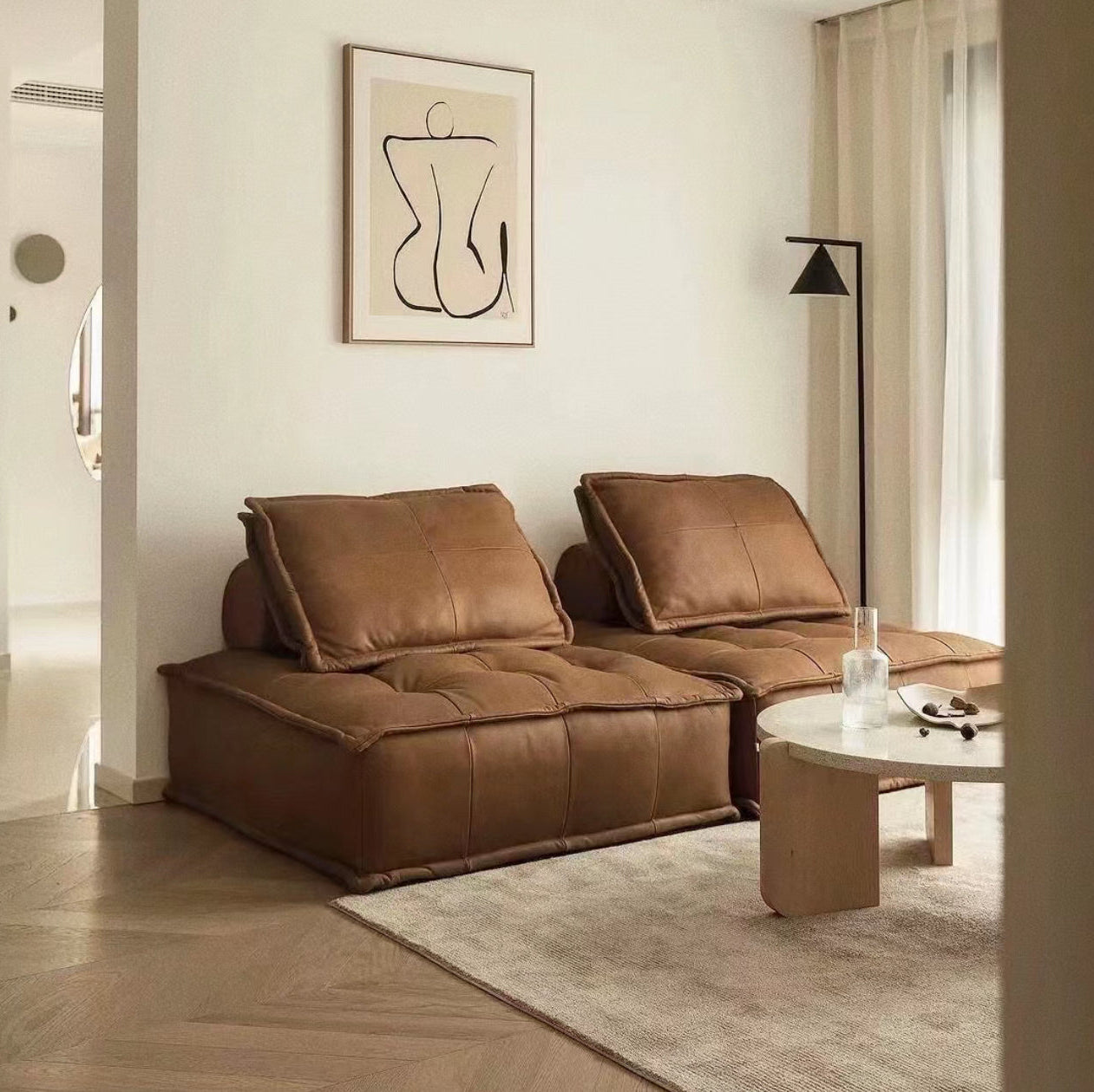 Tofu Modular Sofa in brown leather upholstery styled in cozy minimalist living room with neutral rug and wall art