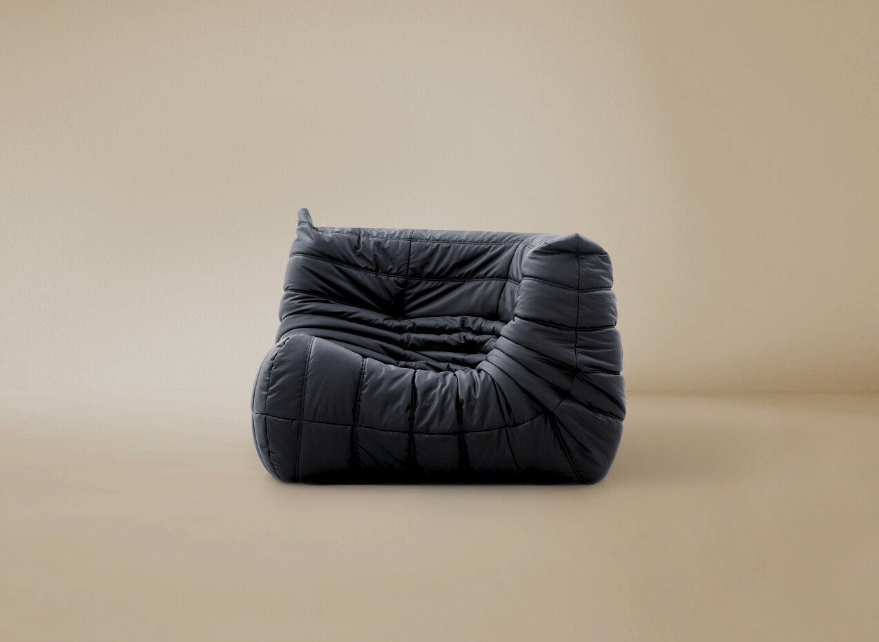 Side angle view of the TOGO corner seat in dark grey showing the curved back support and pleated upholstery.